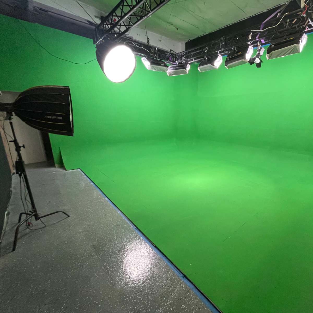 A green screen studio with multiple lights and equipment set up for video production.