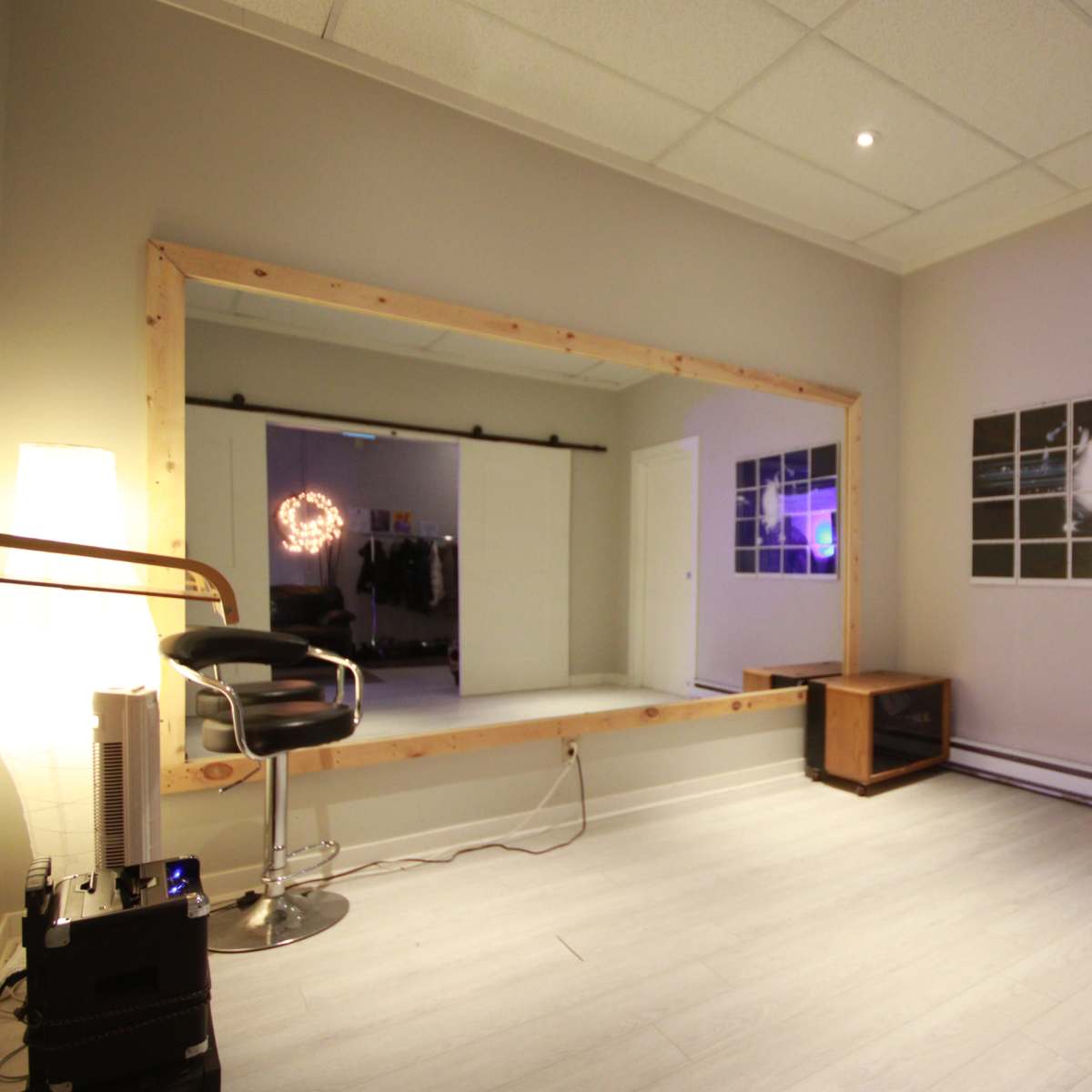 The room features a large wooden-framed mirror, a chair, a small cabinet, and several framed pictures on the walls.