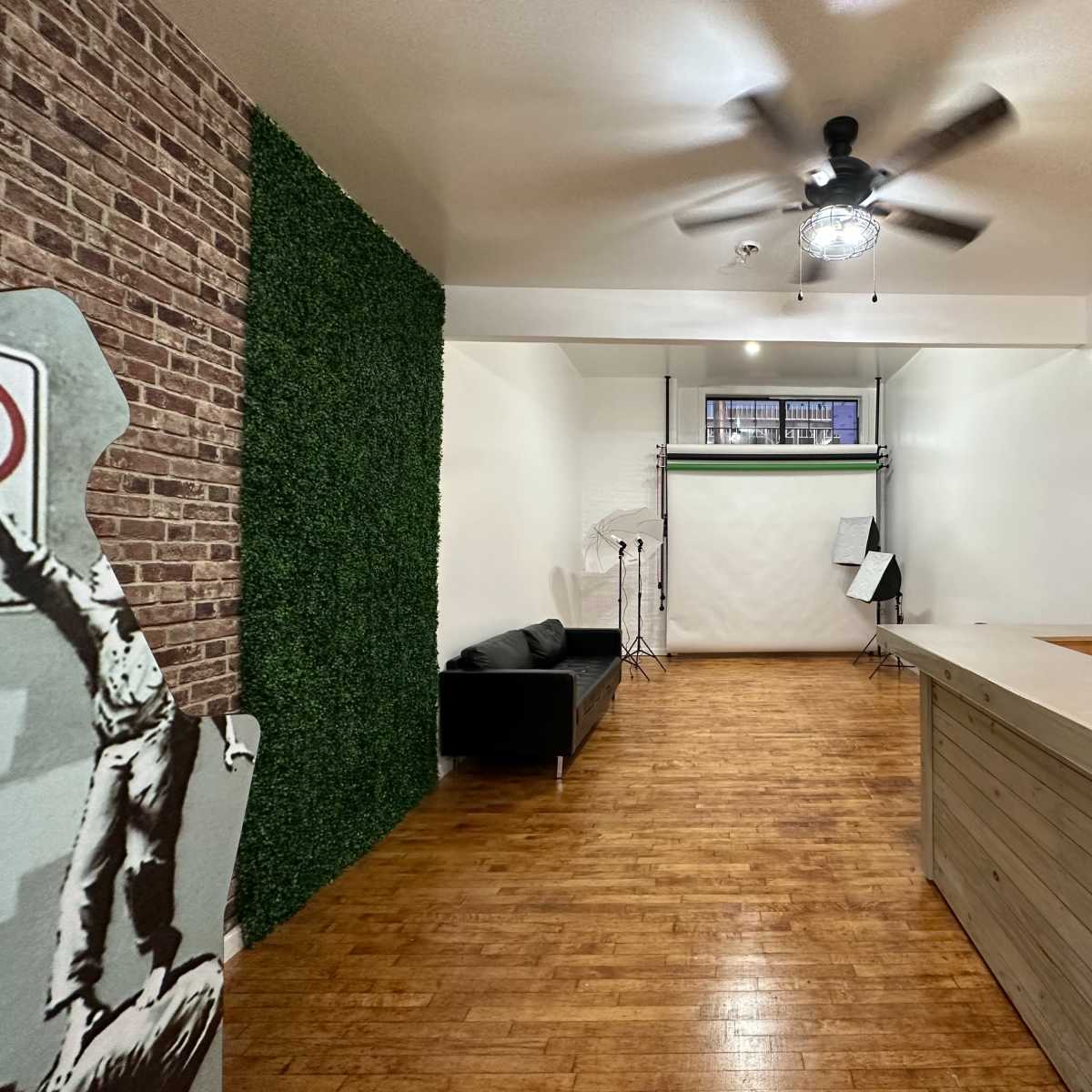 A spacious interior with a wooden floor, a black couch, a reception area, and a large backdrop for photography.