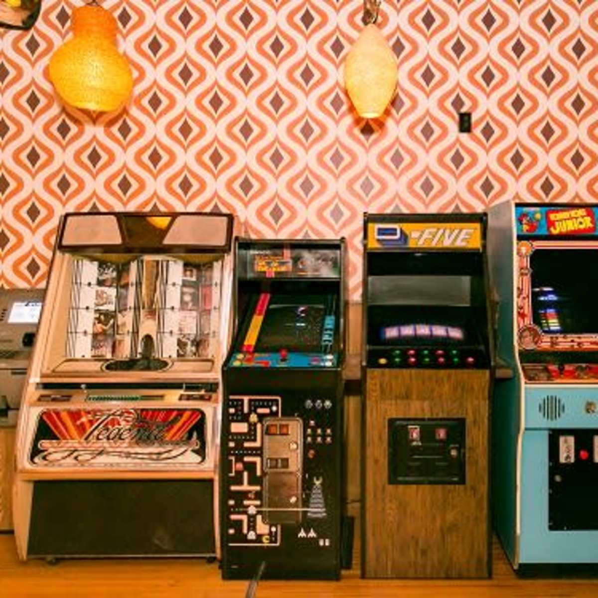 A row of vintage arcade game machines against a patterned wall.