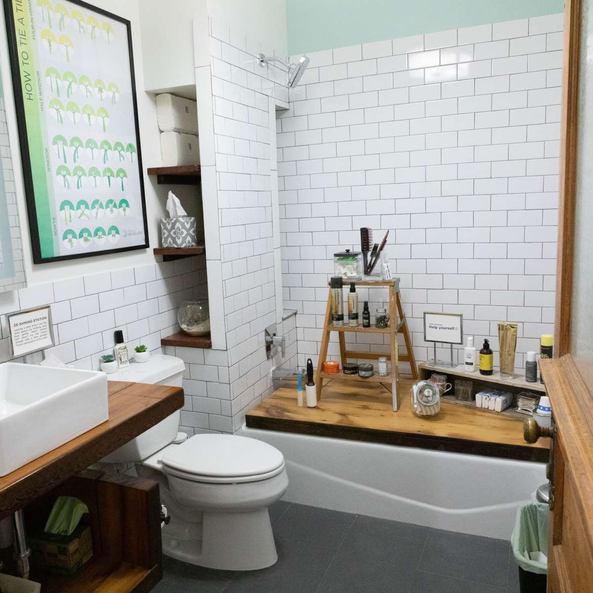 A bathroom featuring white subway tile walls, a wooden countertop with a square sink, and a bathtub with a wooden ledge displaying various toiletries.