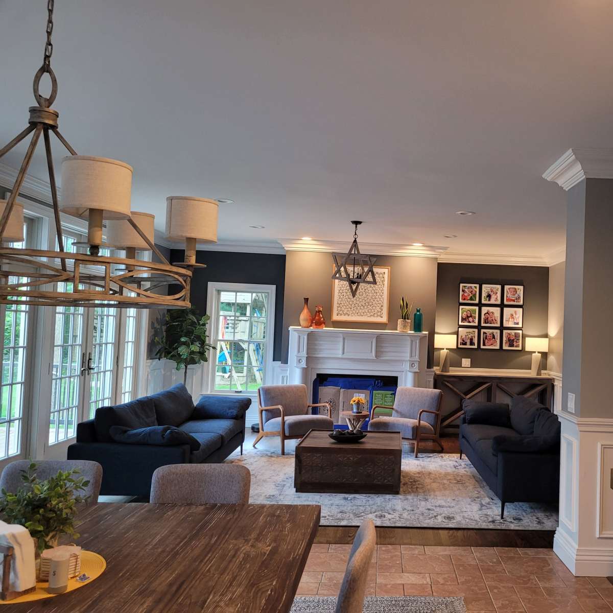 A modern living room featuring a fireplace, framed artwork on the walls, and a dining area with a wooden table and chairs.