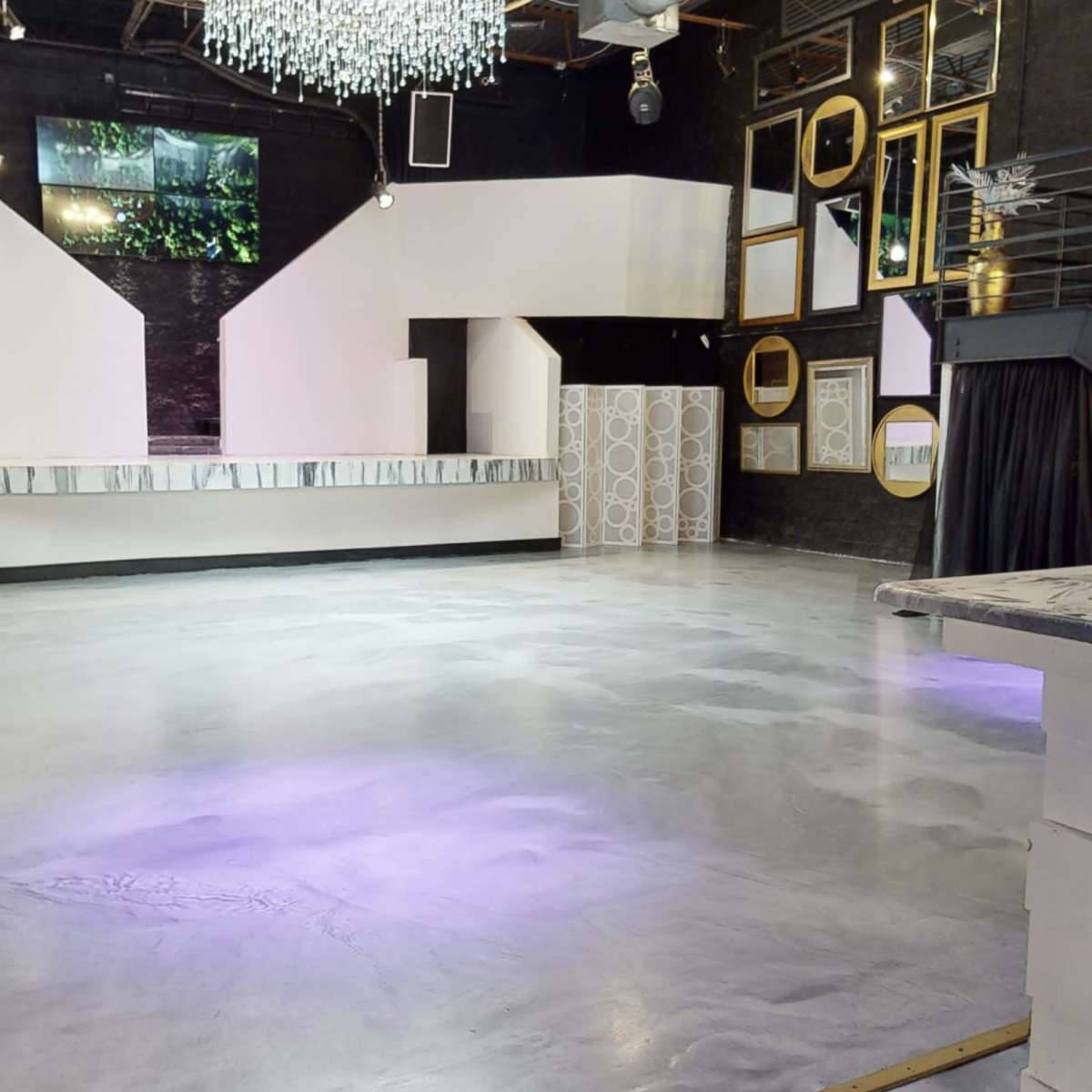 A spacious event venue with a polished concrete floor, a bar area, and decorative mirrors on the walls.