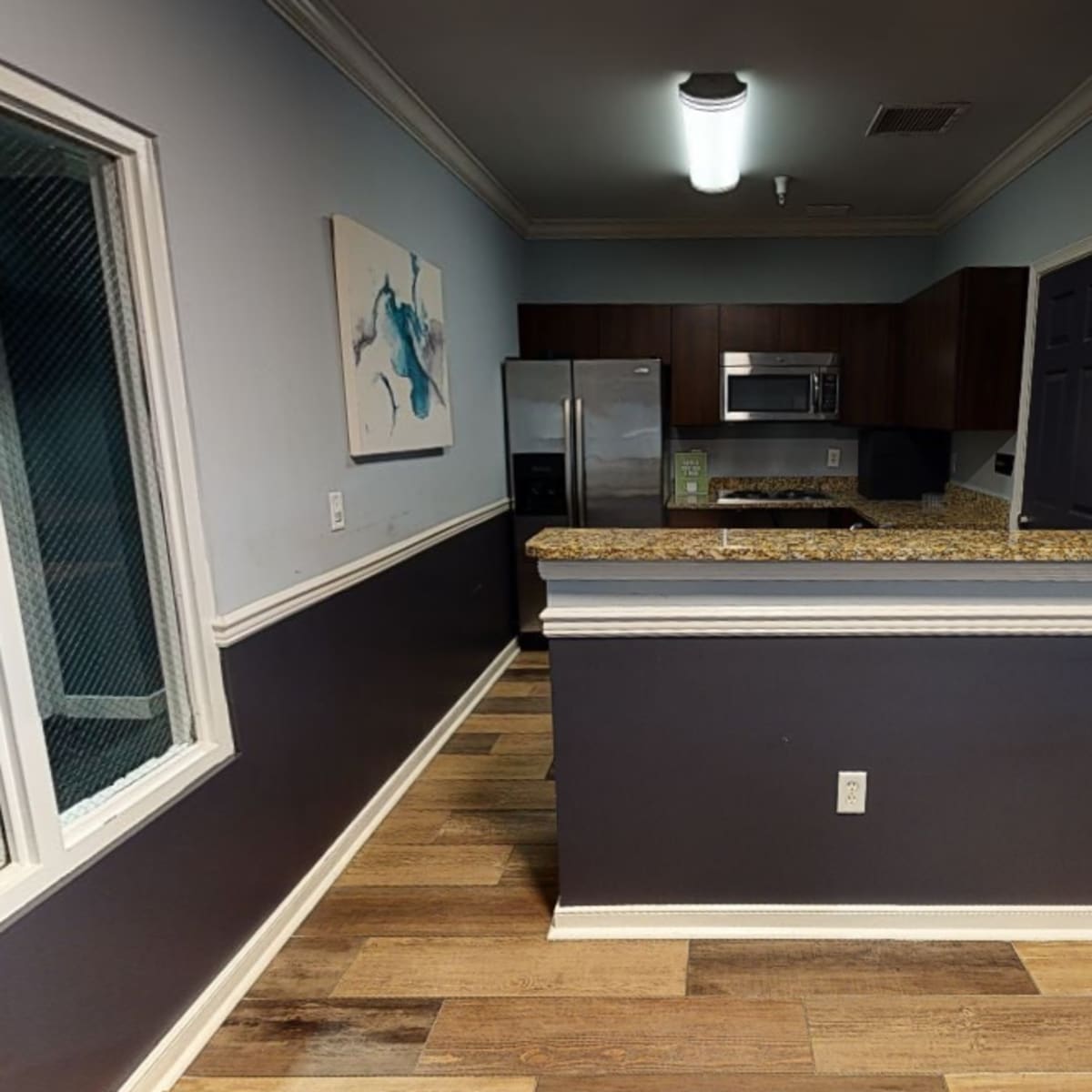 A kitchen area featuring granite countertops, stainless steel appliances, and a combination of blue and dark gray walls.