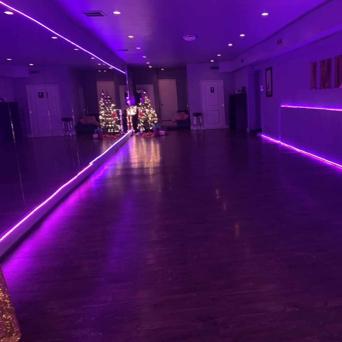 A dance studio with purple LED lighting, a large mirror, and a decorated Christmas tree in the corner.