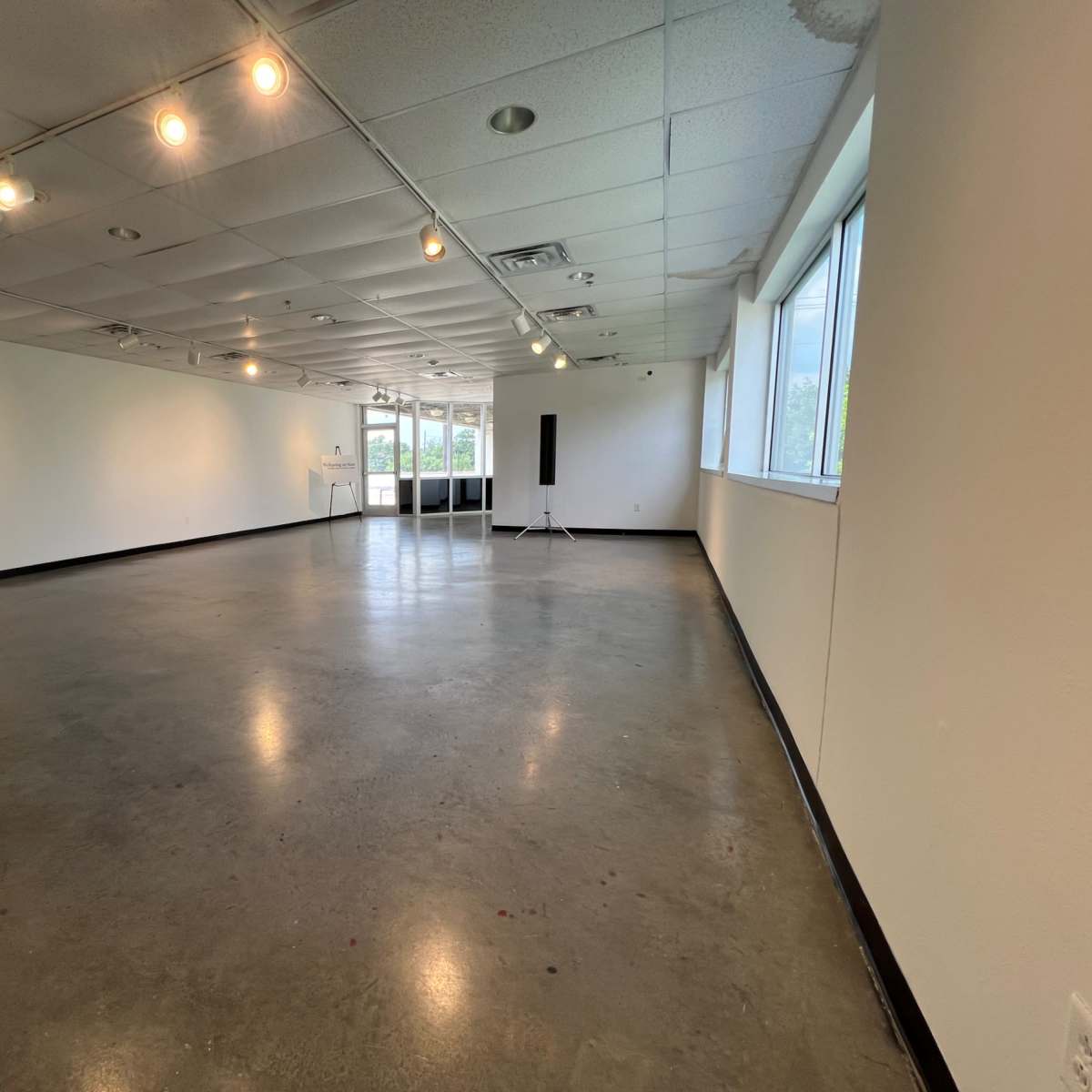 A spacious, empty gallery with polished concrete flooring and overhead lighting.
