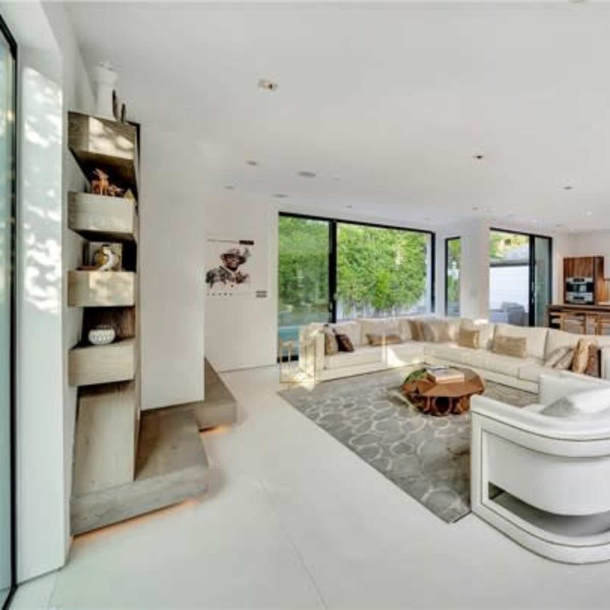 A modern living room with large windows, a sectional sofa, and a view of an outdoor space.