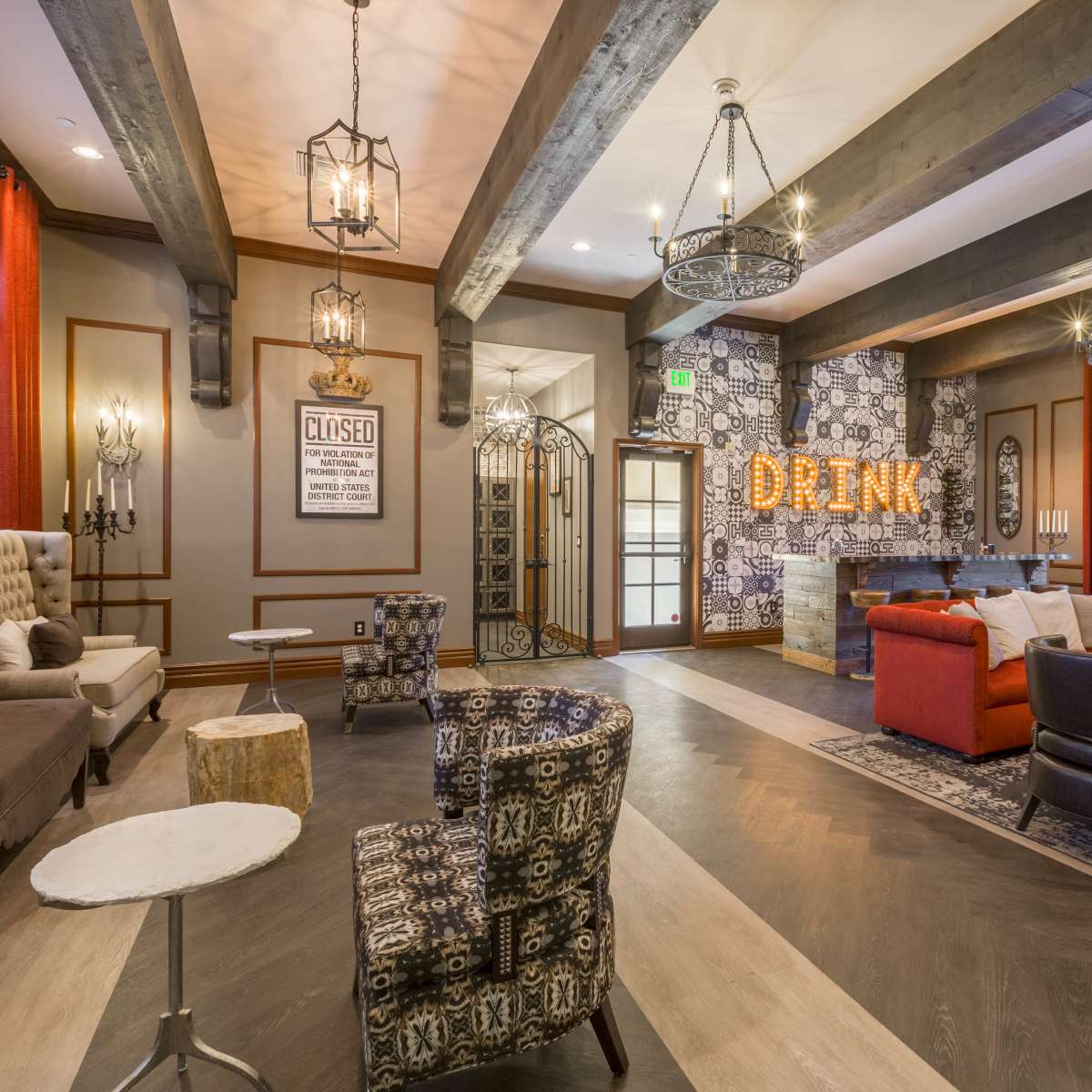 A cozy lounge features a mix of seating arrangements, rustic decor, and illuminated signage reading "DRINK."