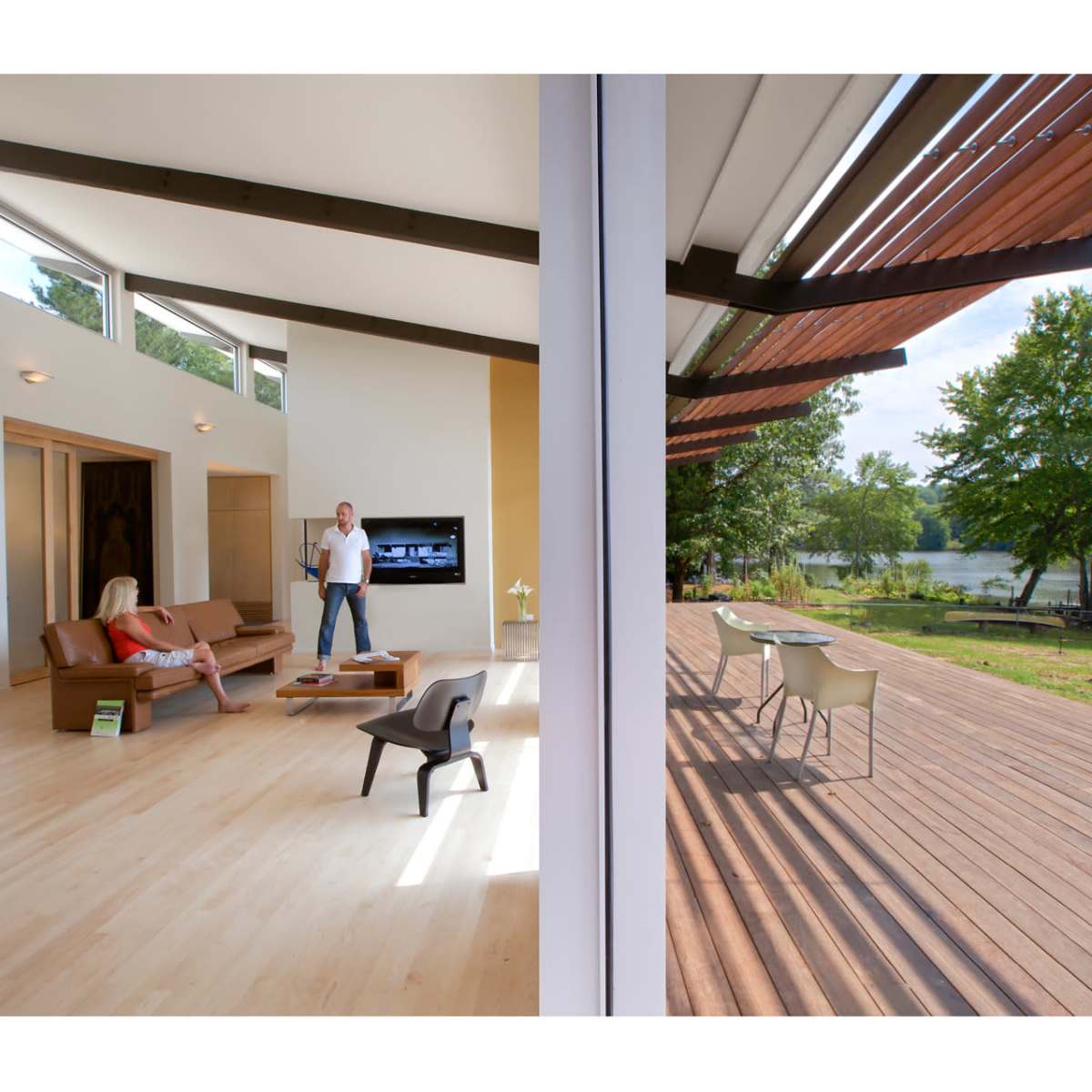A modern living room with a seating area and a view of a deck overlooking a lake.