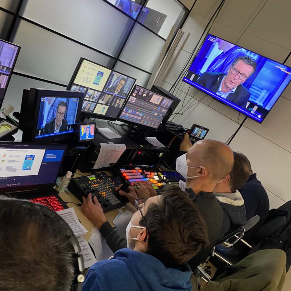 A group of technicians operates broadcasting equipment in a control room while monitoring multiple screens displaying a television program.