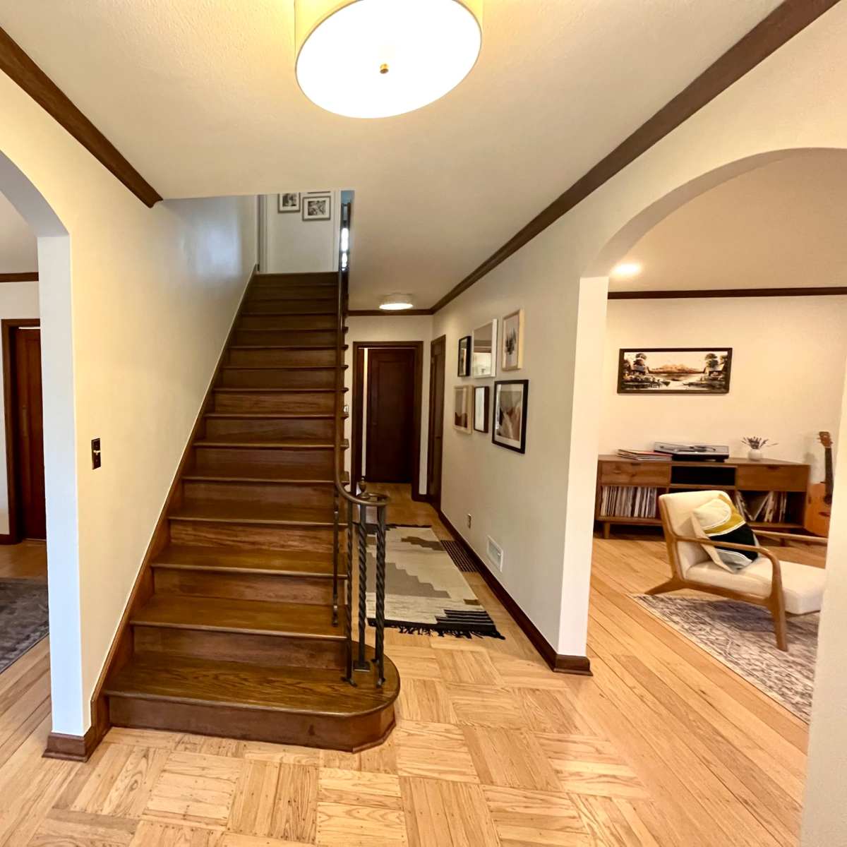 A hallway with a staircase leading to the upper floor, flanked by a dining area on the left and a living space on the right.