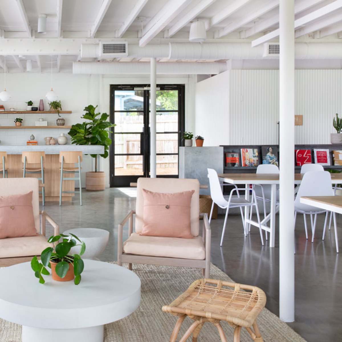 A modern open-plan interior with a seating area featuring two armchairs, a round coffee table, and a kitchen counter in the background.