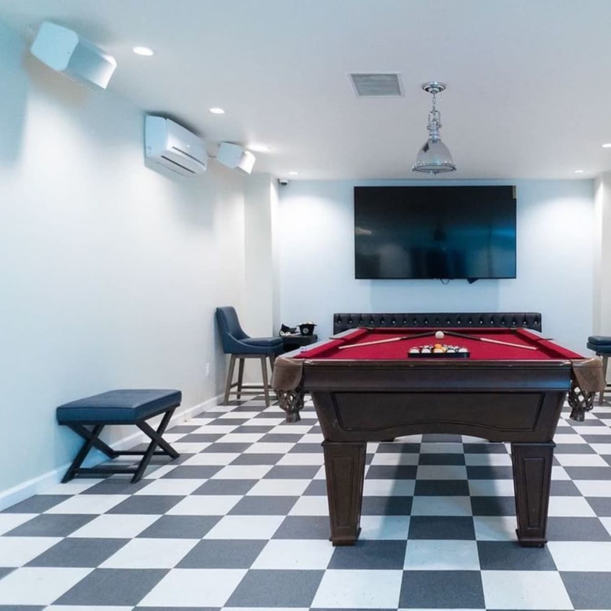 A recreational room featuring a billiard table, a large wall-mounted television, and seating arranged around the space.