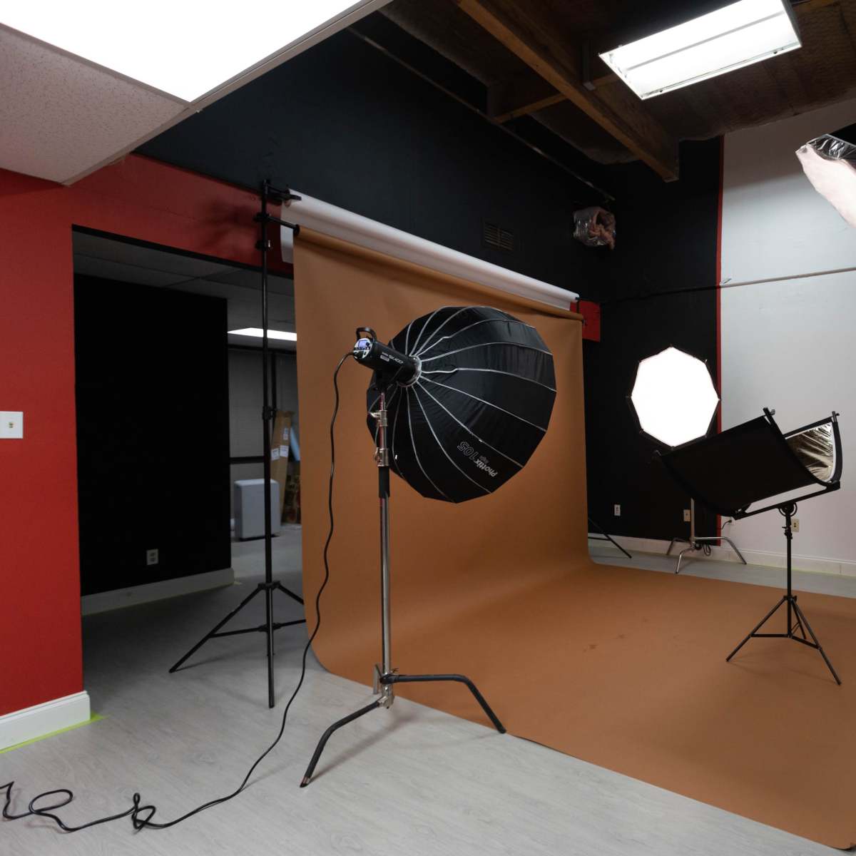A photography studio setup with three light umbrellas and a brown backdrop.