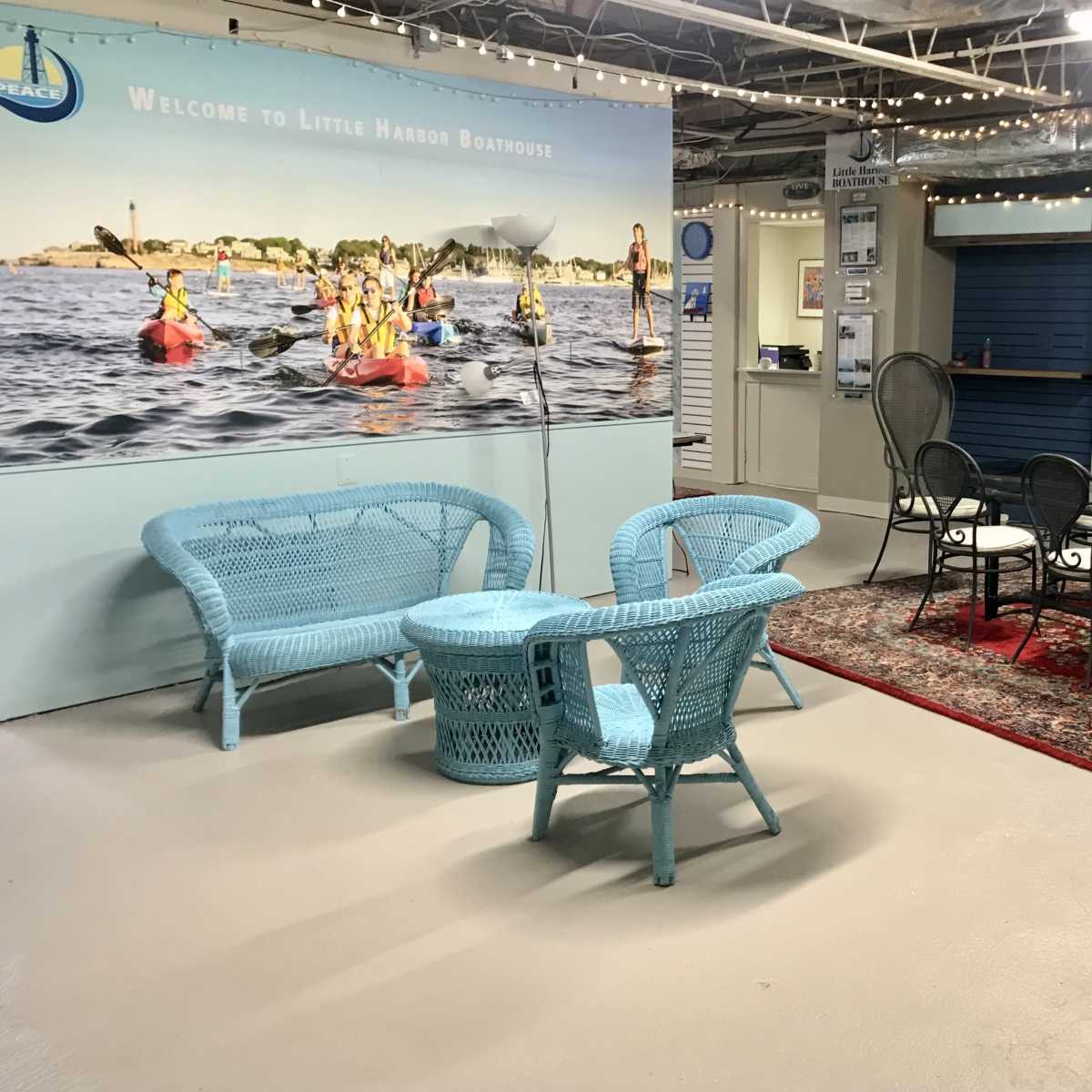 A recreational space with blue wicker furniture and a backdrop featuring a kayaking scene.