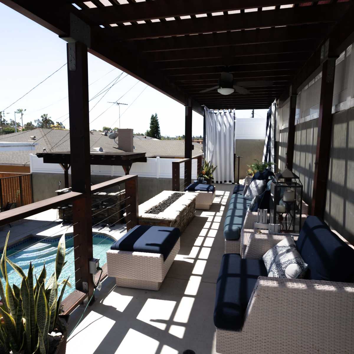 A covered patio features seating areas and a view of a pool surrounded by well-maintained landscaping.