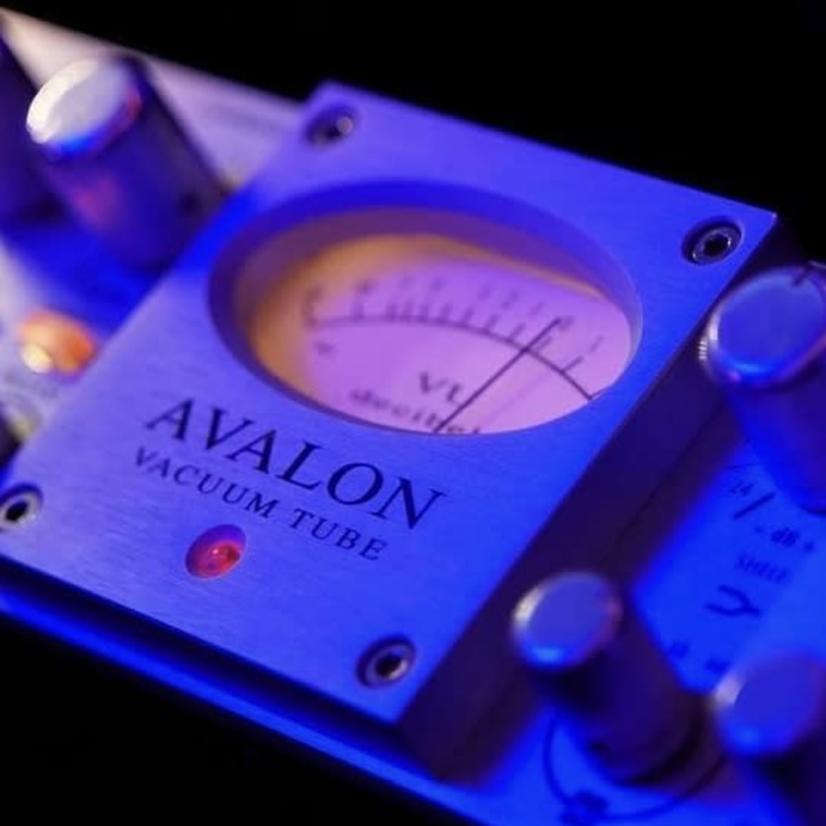 A close-up of an Avalon vacuum tube audio equipment with a gauge displaying levels, illuminated by blue lighting.