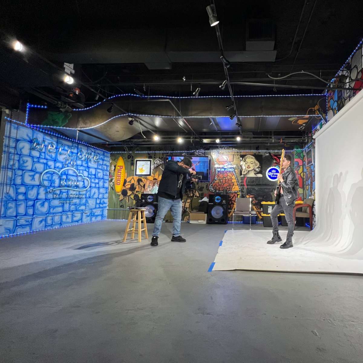 A photographer captures a model posing against a white backdrop in a creatively decorated studio featuring colorful murals.