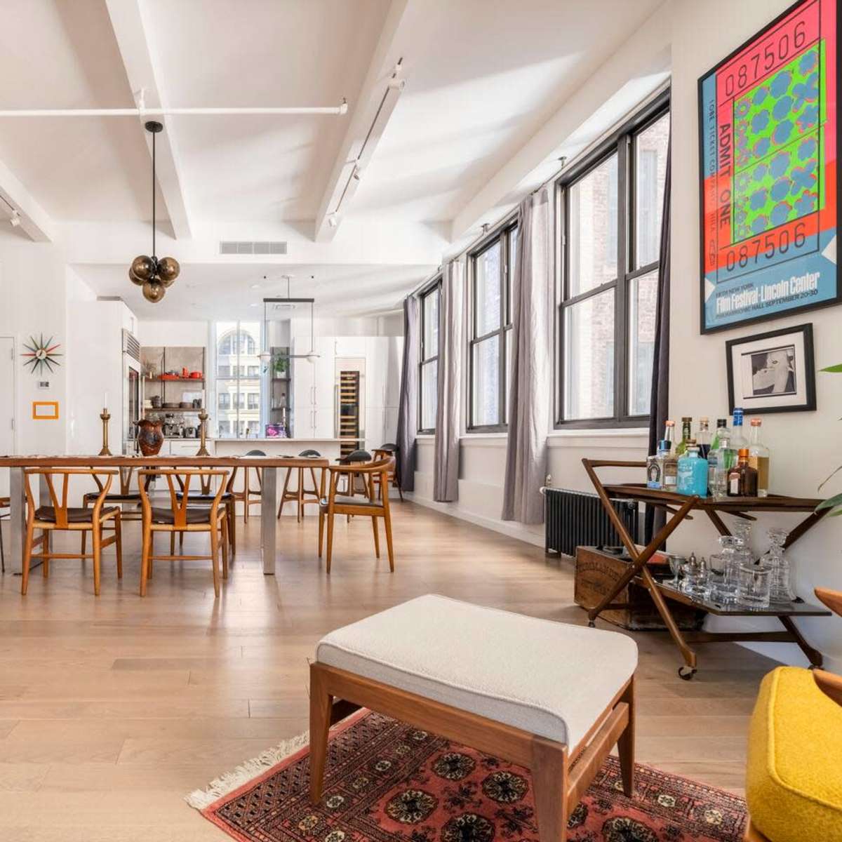 A spacious, well-lit open-plan living area with a dining table, modern furniture, and large windows.