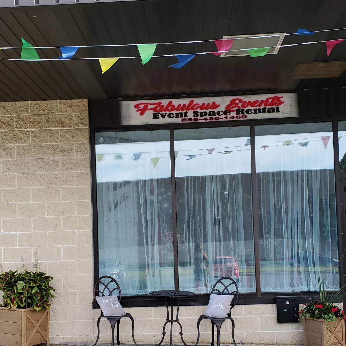 The entrance of a venue called "Fabulous Events," featuring a small table with two chairs and decorative planters on either side.