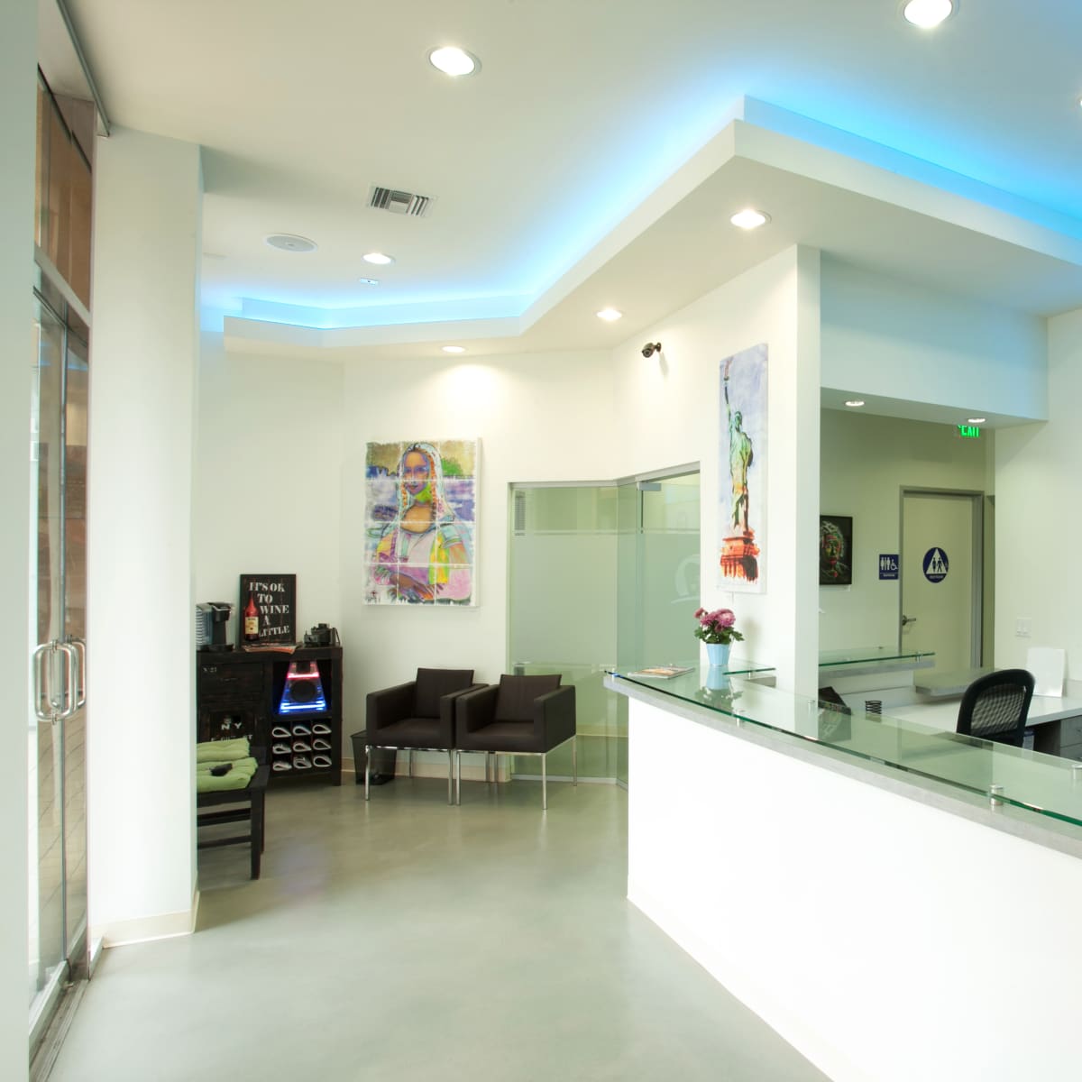A modern reception area with a glass counter, seating area, and decorative artwork on the walls.
