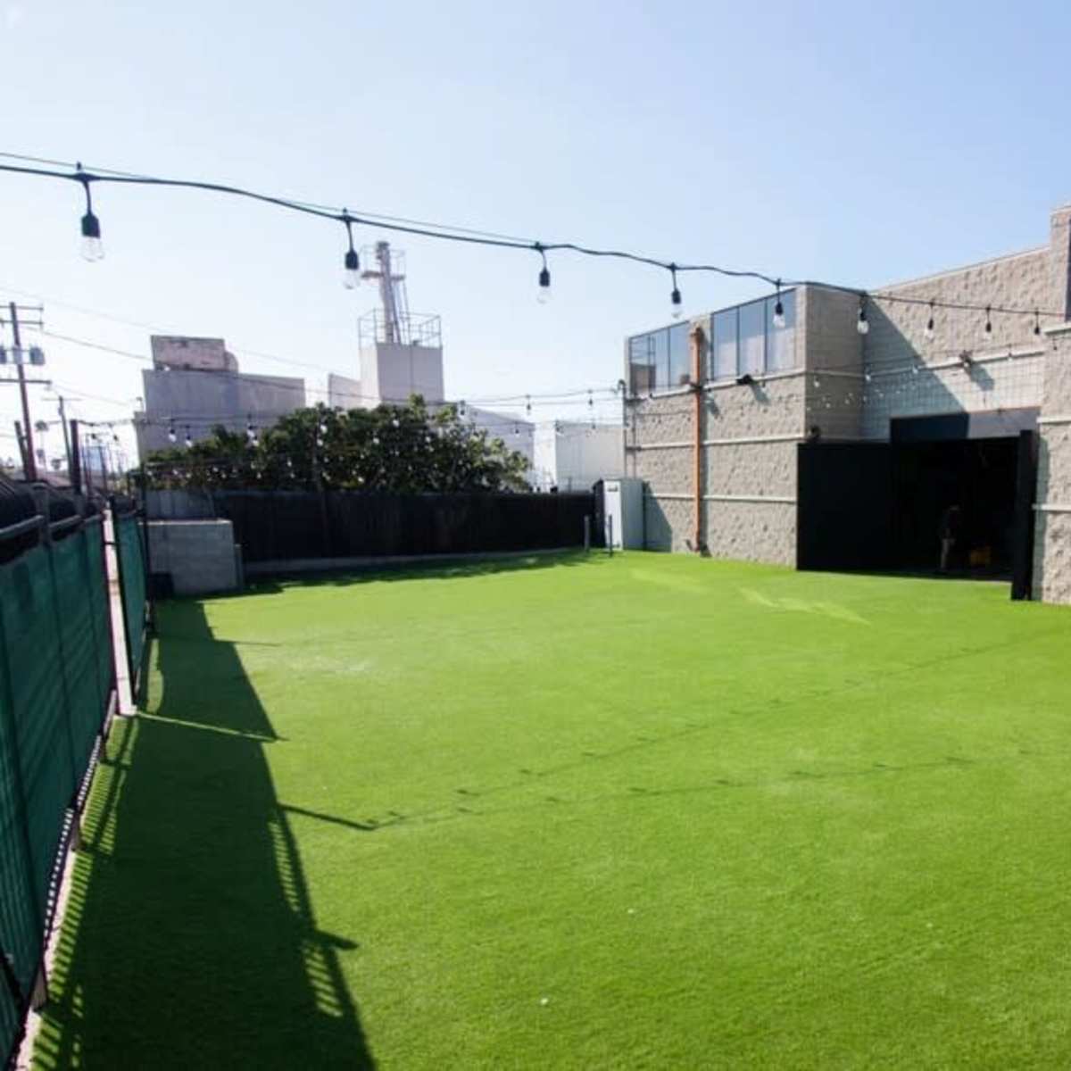 A vacant, well-maintained artificial grass area adjacent to a building with multiple windows.