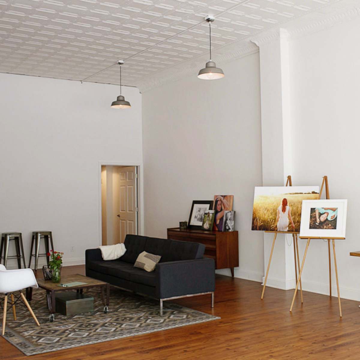 A spacious, modern interior with a couch, wooden furniture, and artwork displayed on easels.