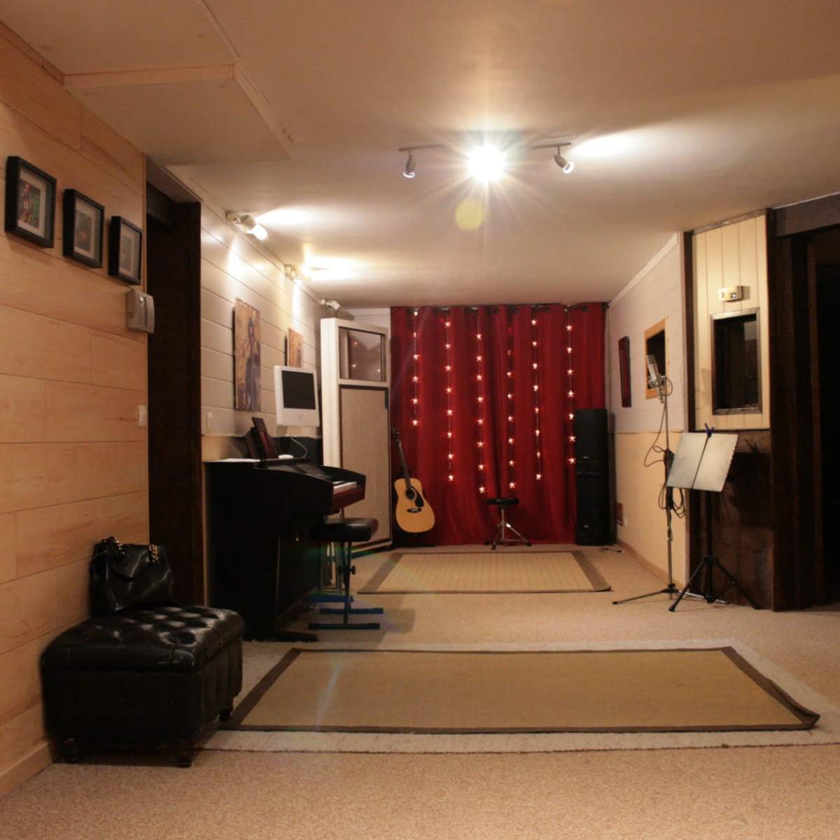 A hallway features wooden paneling, a black piano, an acoustic guitar, and a red curtain adorned with string lights.