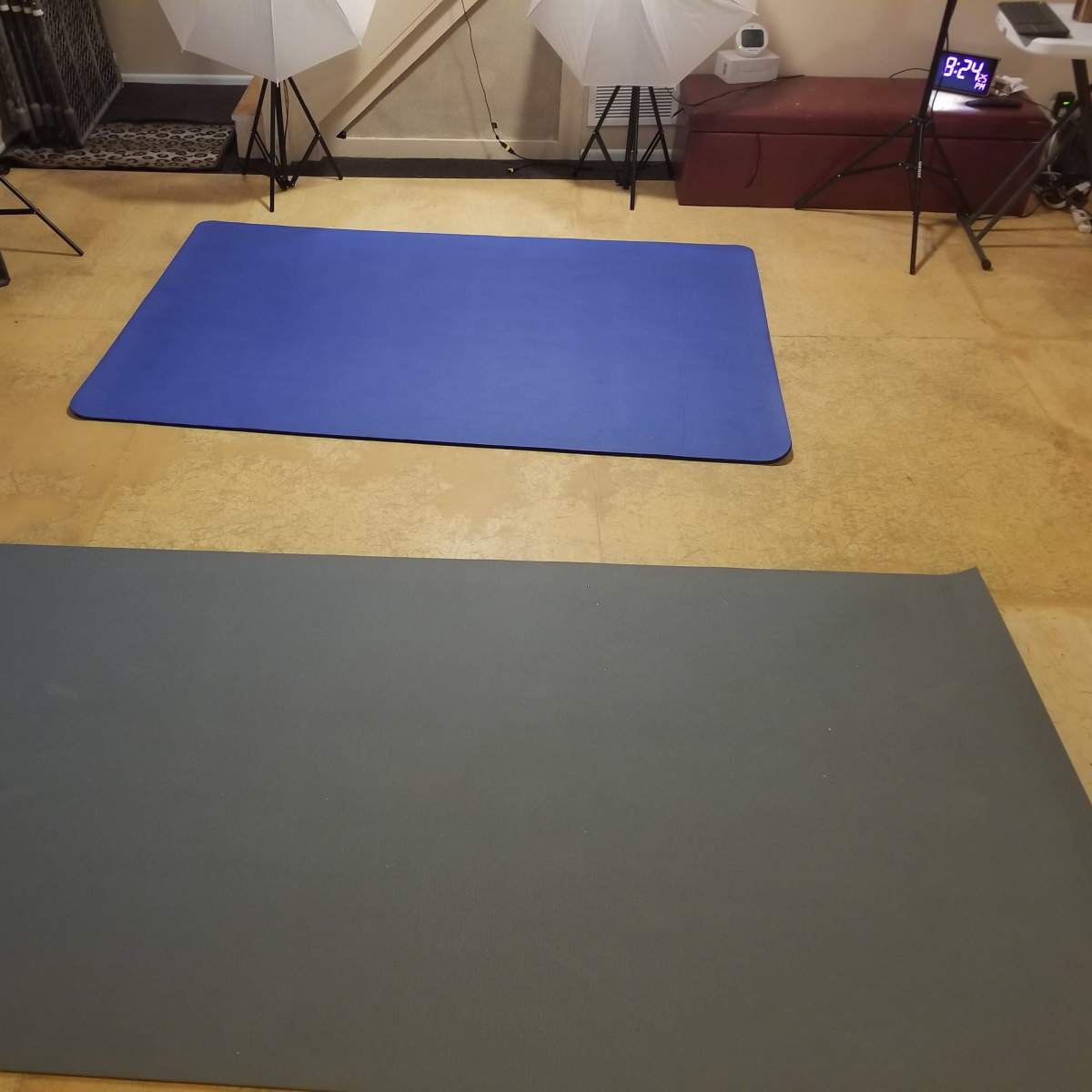 Two exercise mats on a textured floor, with a clock and lighting equipment in the background.
