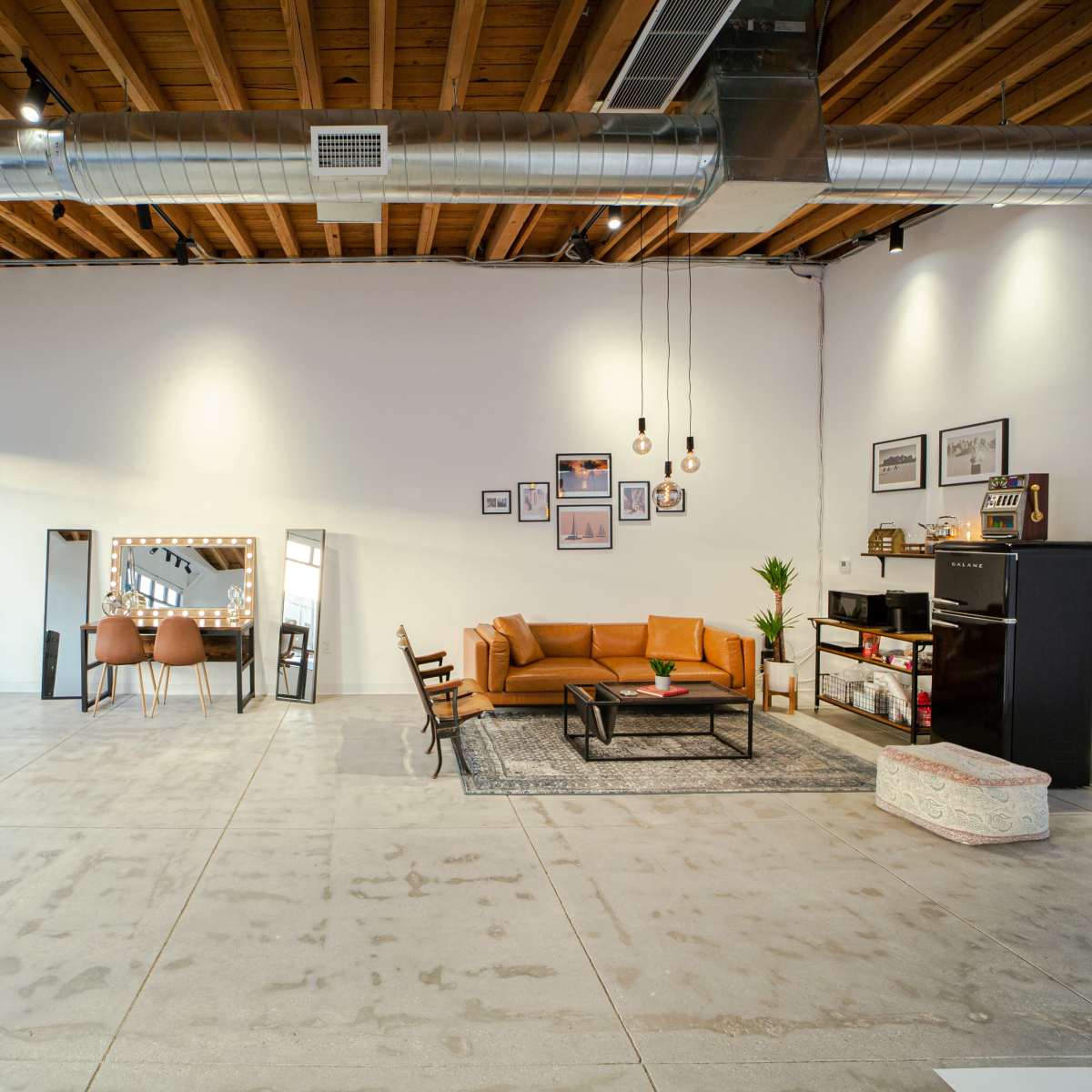 A modern, open interior space featuring a sofa, a coffee table, a dining area with chairs, and various decorative elements.
