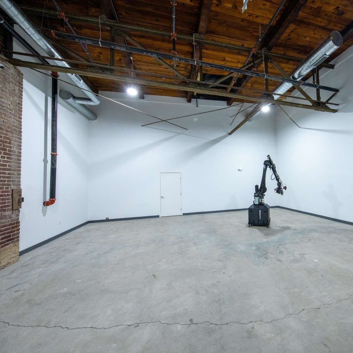 An empty industrial room with a robotic arm positioned at the center.