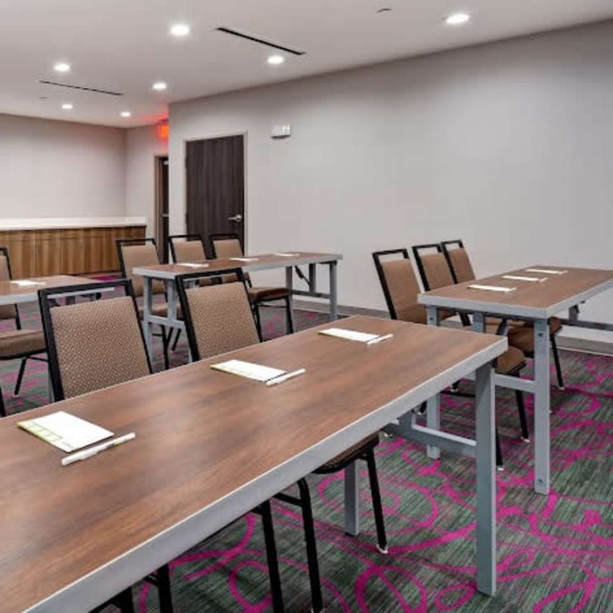 A conference room arranged with multiple tables and chairs, ready for a meeting or presentation.