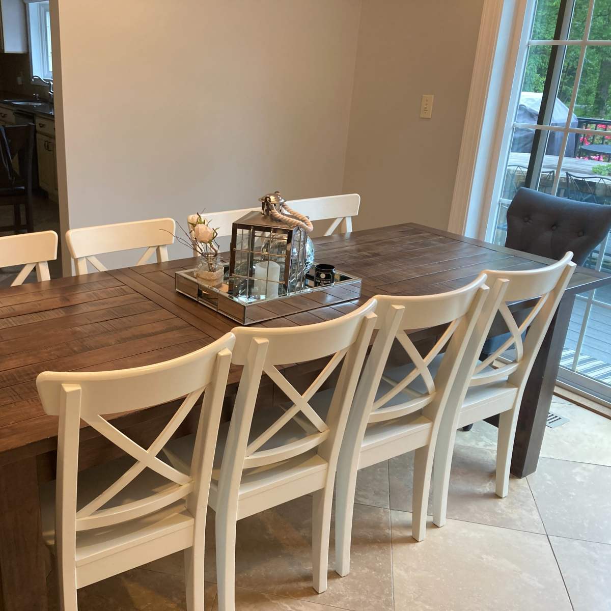 A wooden dining table with white chairs is set in a well-lit room, with a glass decorative centerpiece on the table.