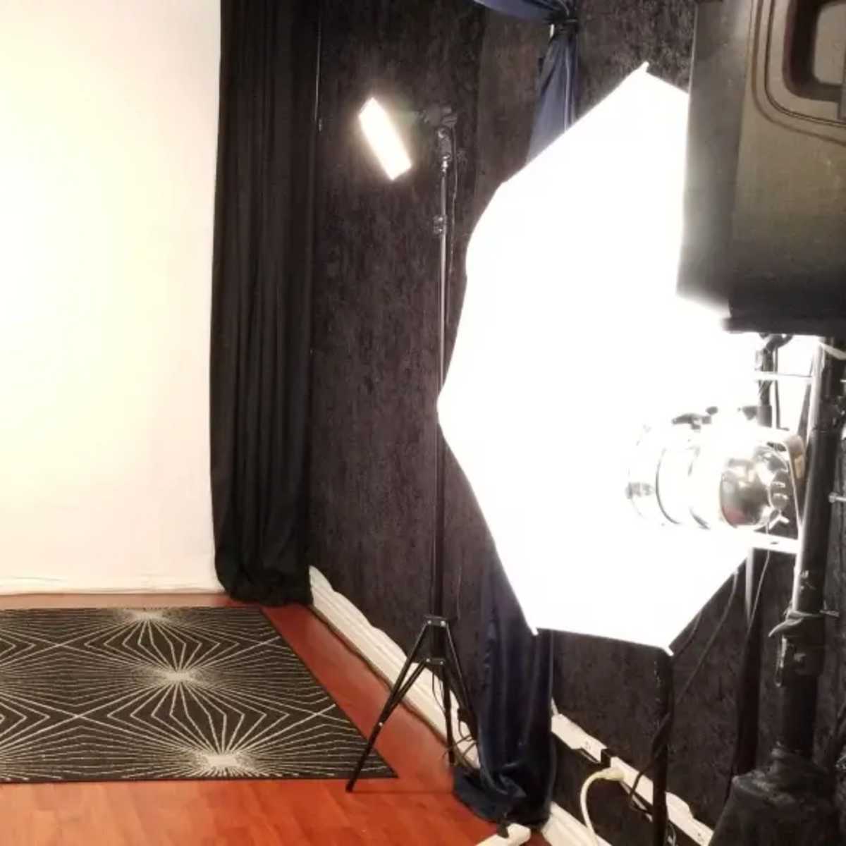 A photography studio setup with white backdrop, black curtains, and bright lights positioned on either side.