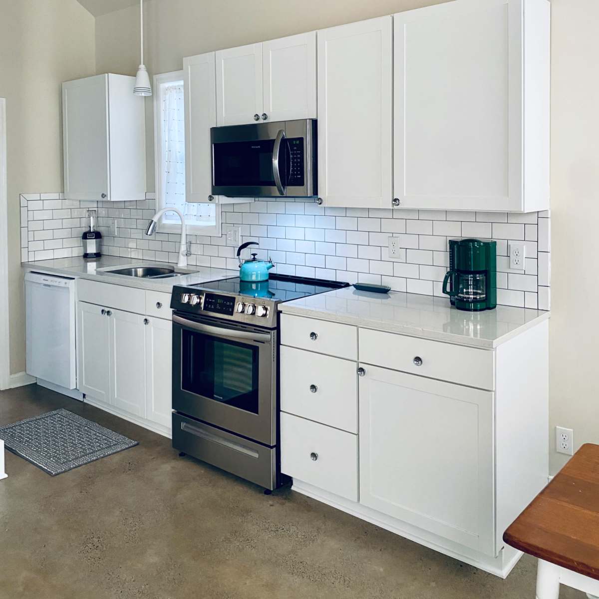 A modern kitchen featuring white cabinetry, stainless steel appliances, and a tiled backsplash.