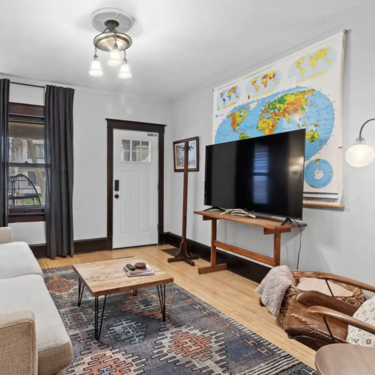 A living room features a neutral sofa, a wooden coffee table, a large TV on a stand, and a world map hanging on the wall.