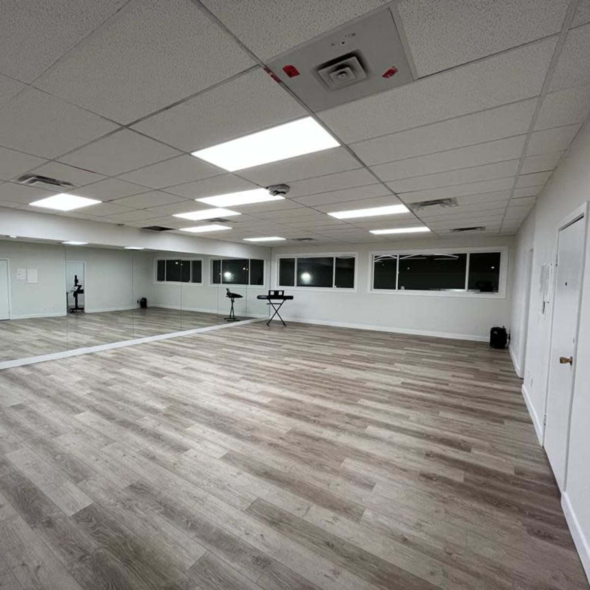An empty, well-lit studio space with wooden flooring and large windows.