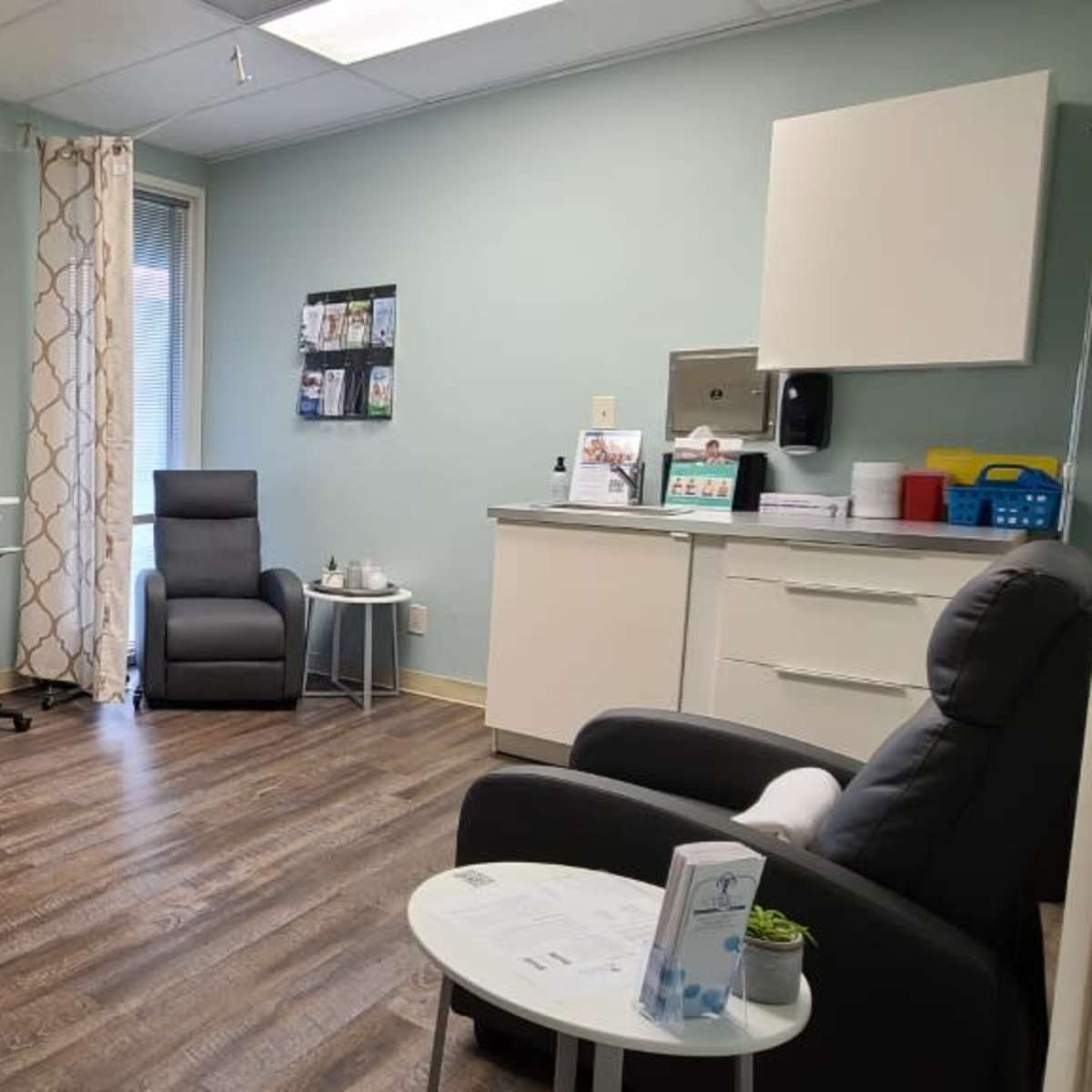 A small, well-lit office with two chairs, a desk, and a cabinet against light blue walls.