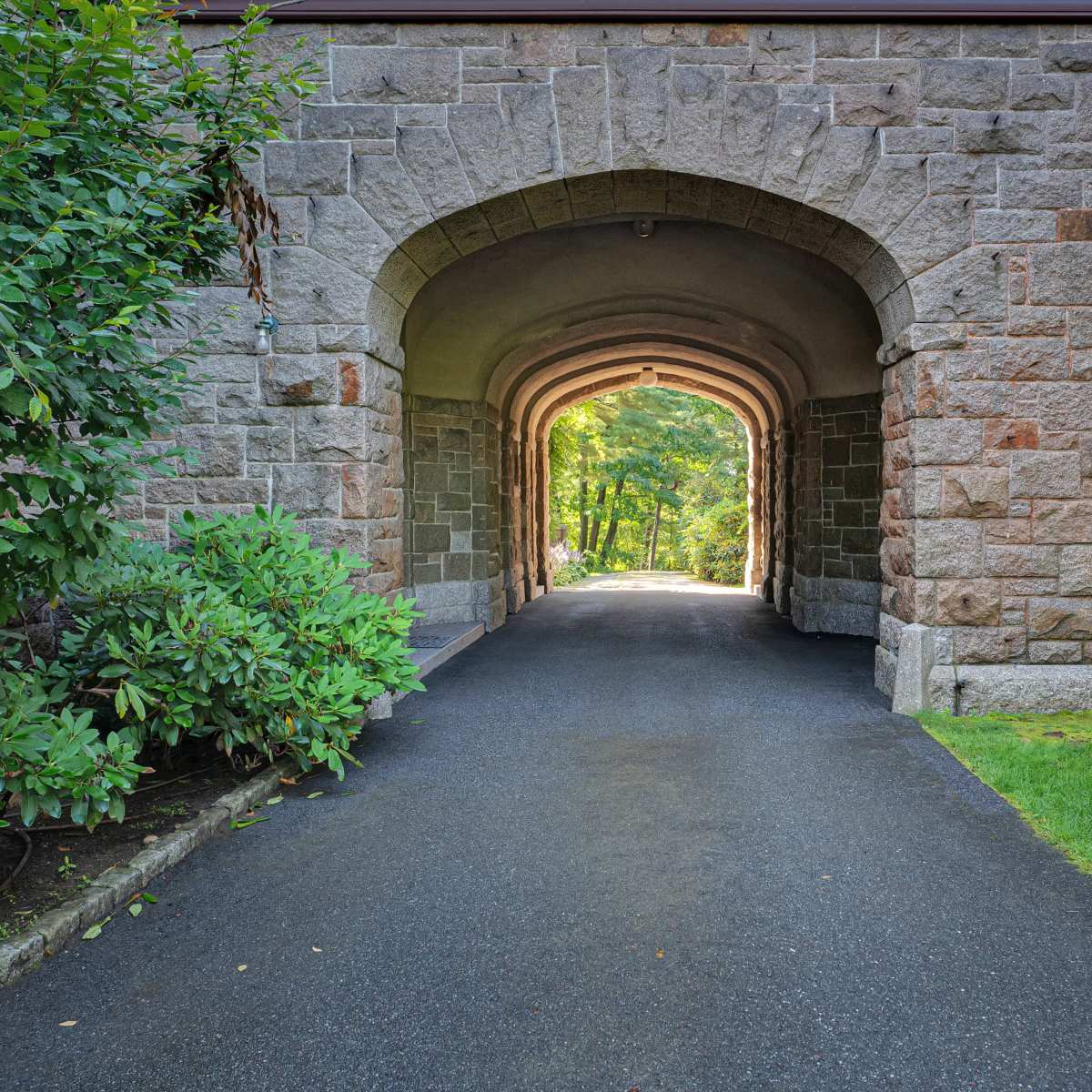 A stone archway leading to a tree-lined pathway.