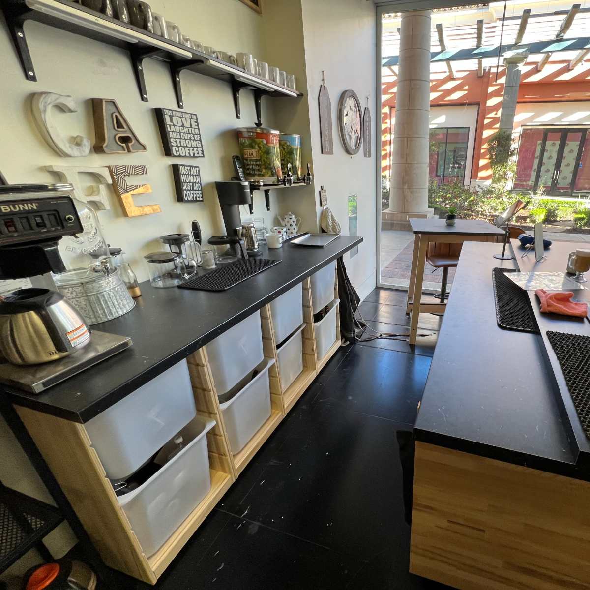 A well-organized coffee preparation area with a counter featuring various utensils, containers, and a coffee machine.