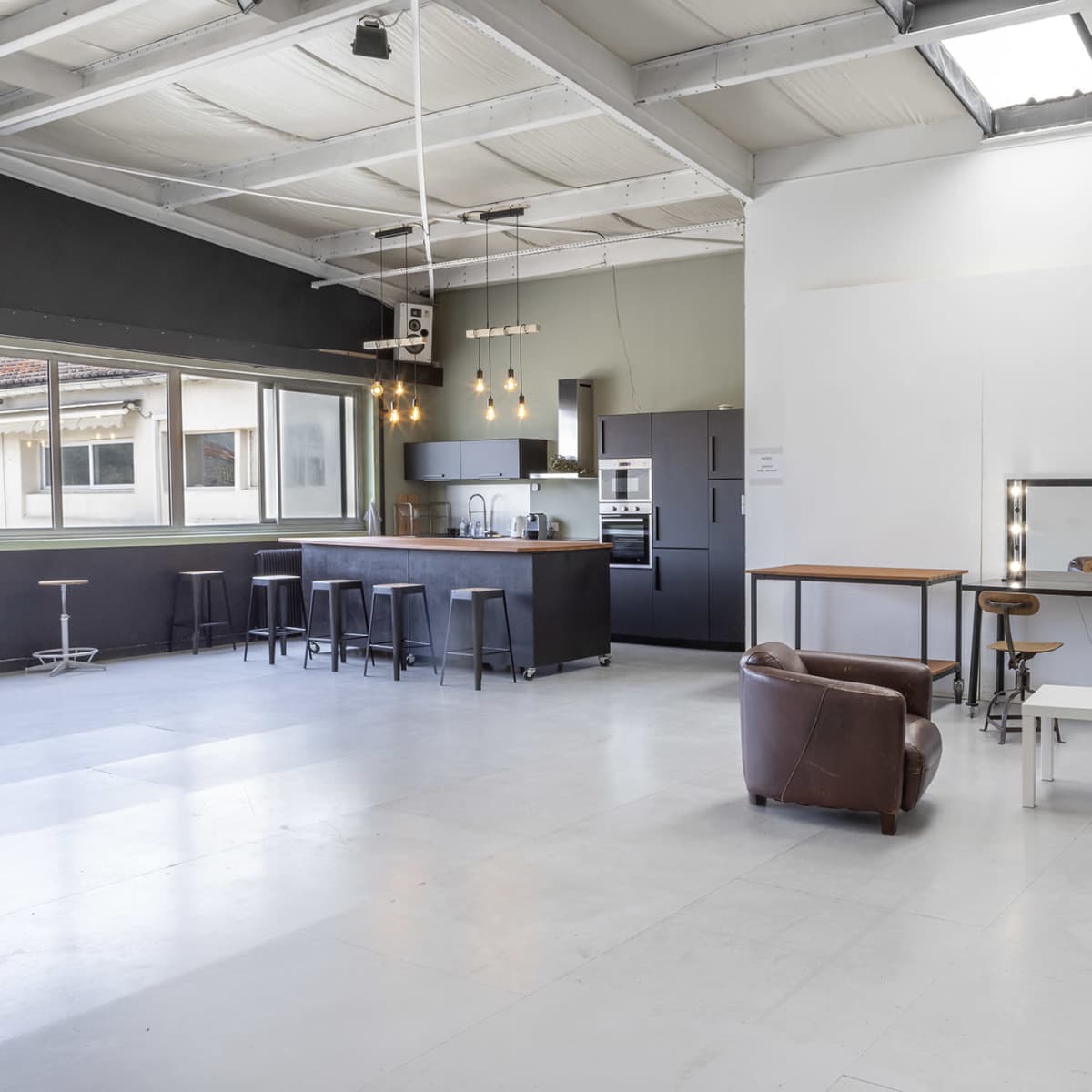 A spacious, modern interior with a kitchenette, seating area, and a bicycle propped against the wall.
