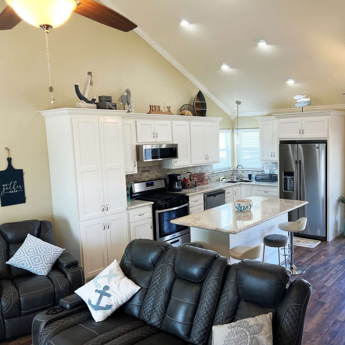 A modern kitchen and living area with white cabinetry, stainless steel appliances, and a comfortable seating arrangement.