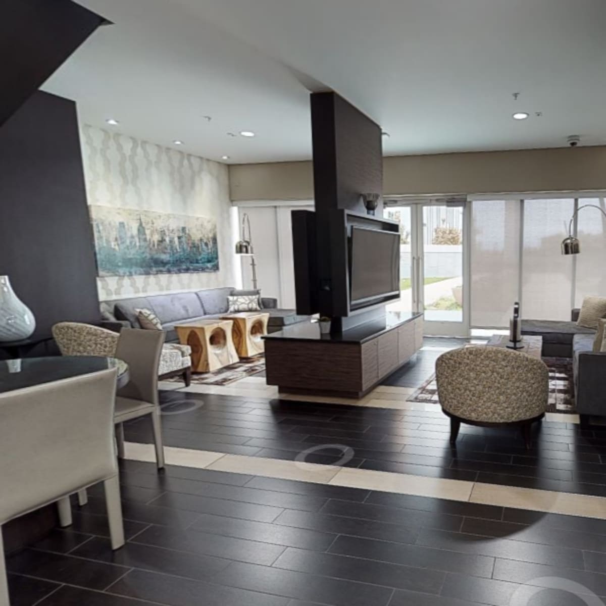 A modern open-concept living area with a kitchen and a seating area featuring a large television and outdoor views.