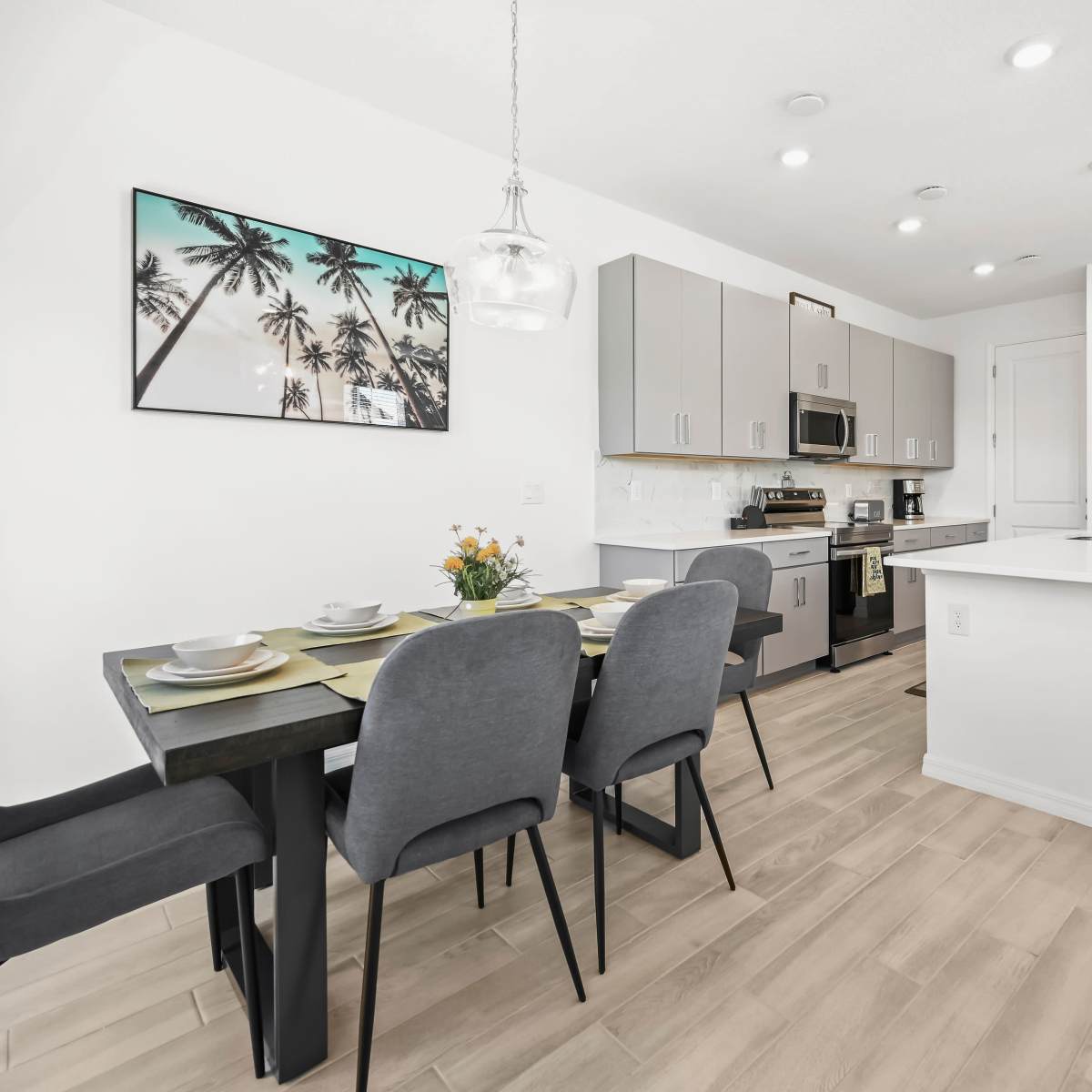 A modern kitchen and dining area feature a table set for six and sleek, contemporary appliances.