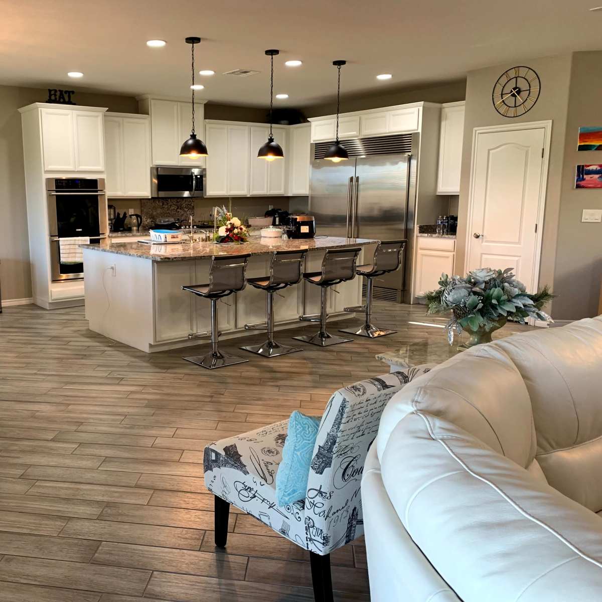 A modern kitchen and dining area featuring a large island with bar stools, a dining table, and light-colored cabinetry.