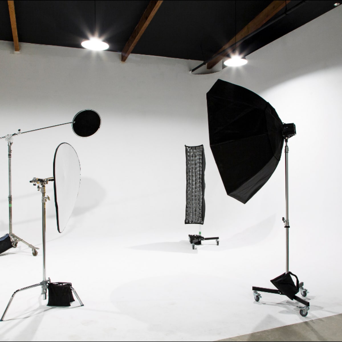 A photography studio with various lighting equipment, including a softbox, reflectors, and a backdrop setup.