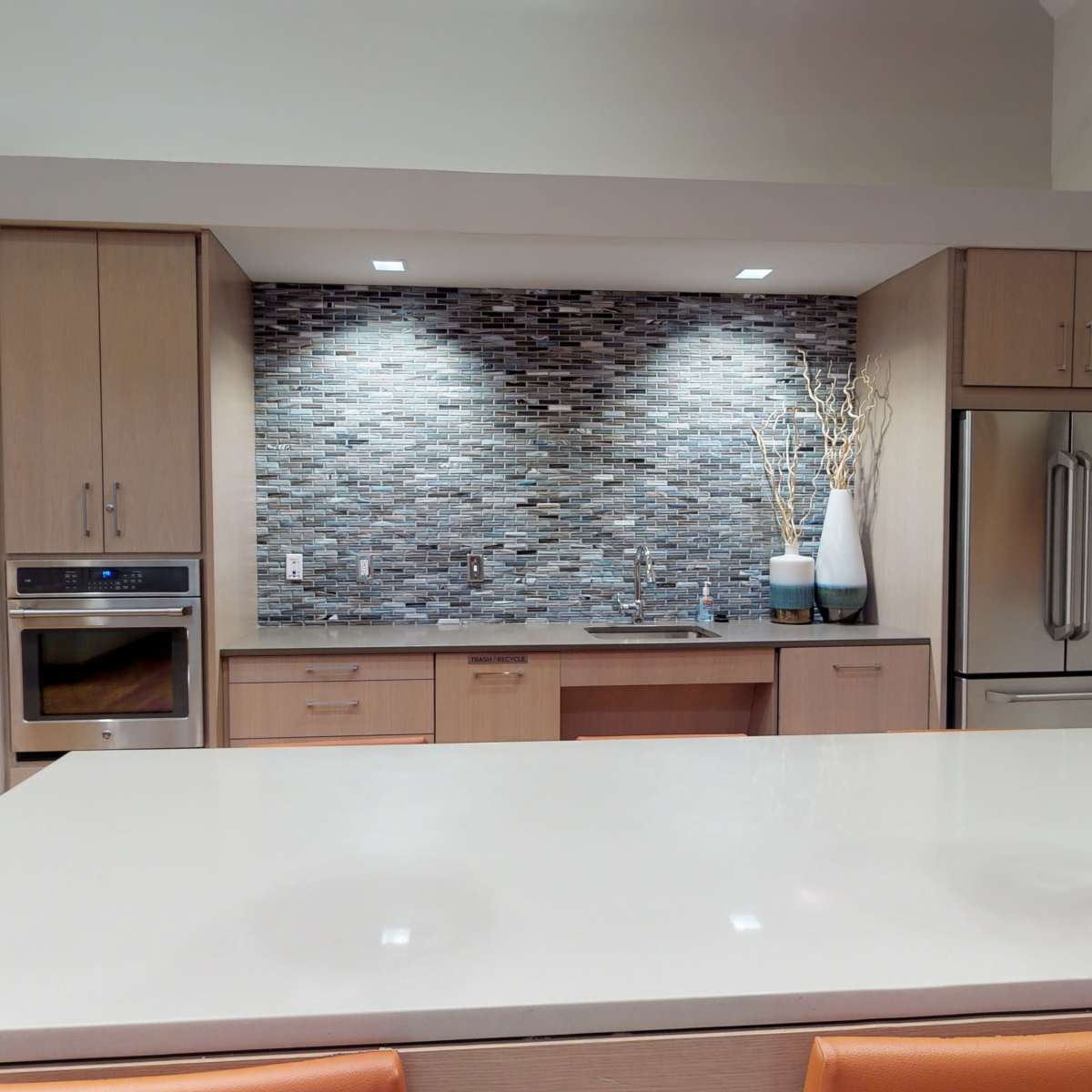 The kitchen features a modern design with a large island, sleek cabinetry, and a tiled backsplash.