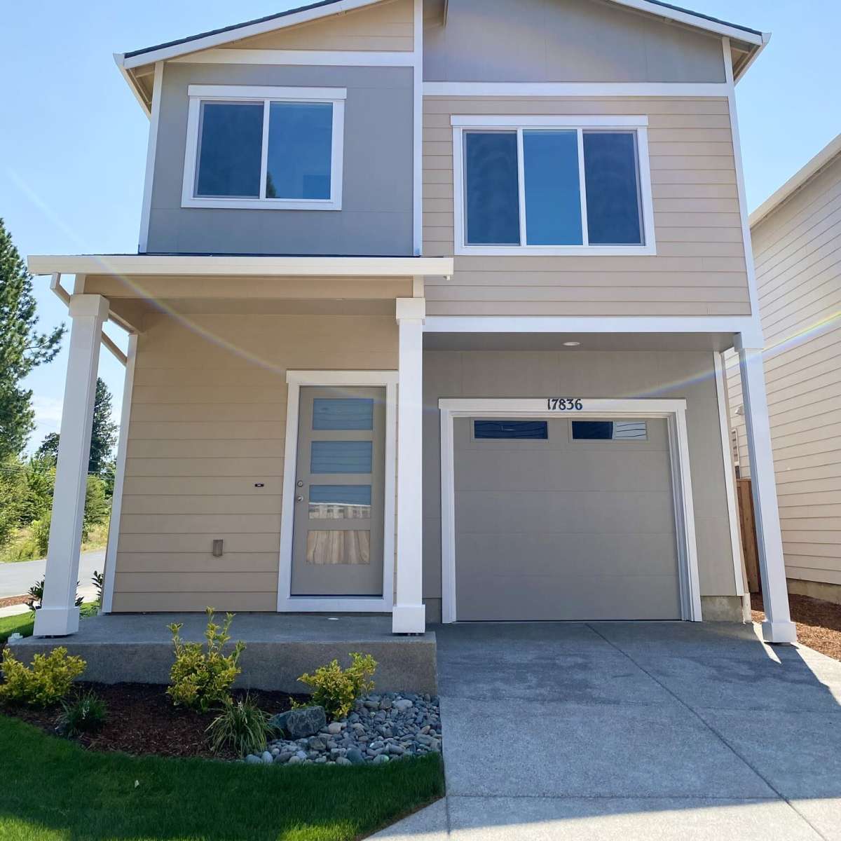 A two-story modern house with a light-colored exterior and a concrete driveway.