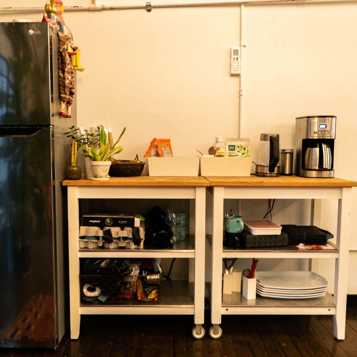 A kitchen area featuring a stainless steel refrigerator, a coffee maker, and a countertop with various kitchen utensils and supplies.