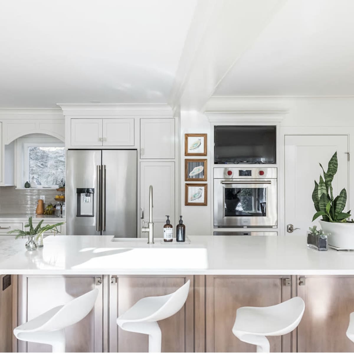 The kitchen features modern appliances, a white marble countertop with bar seating, and light-colored cabinetry.
